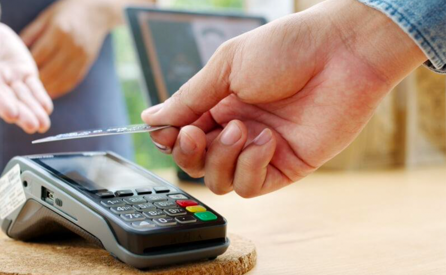 Mano con una tarjeta pagando en un datáfono
