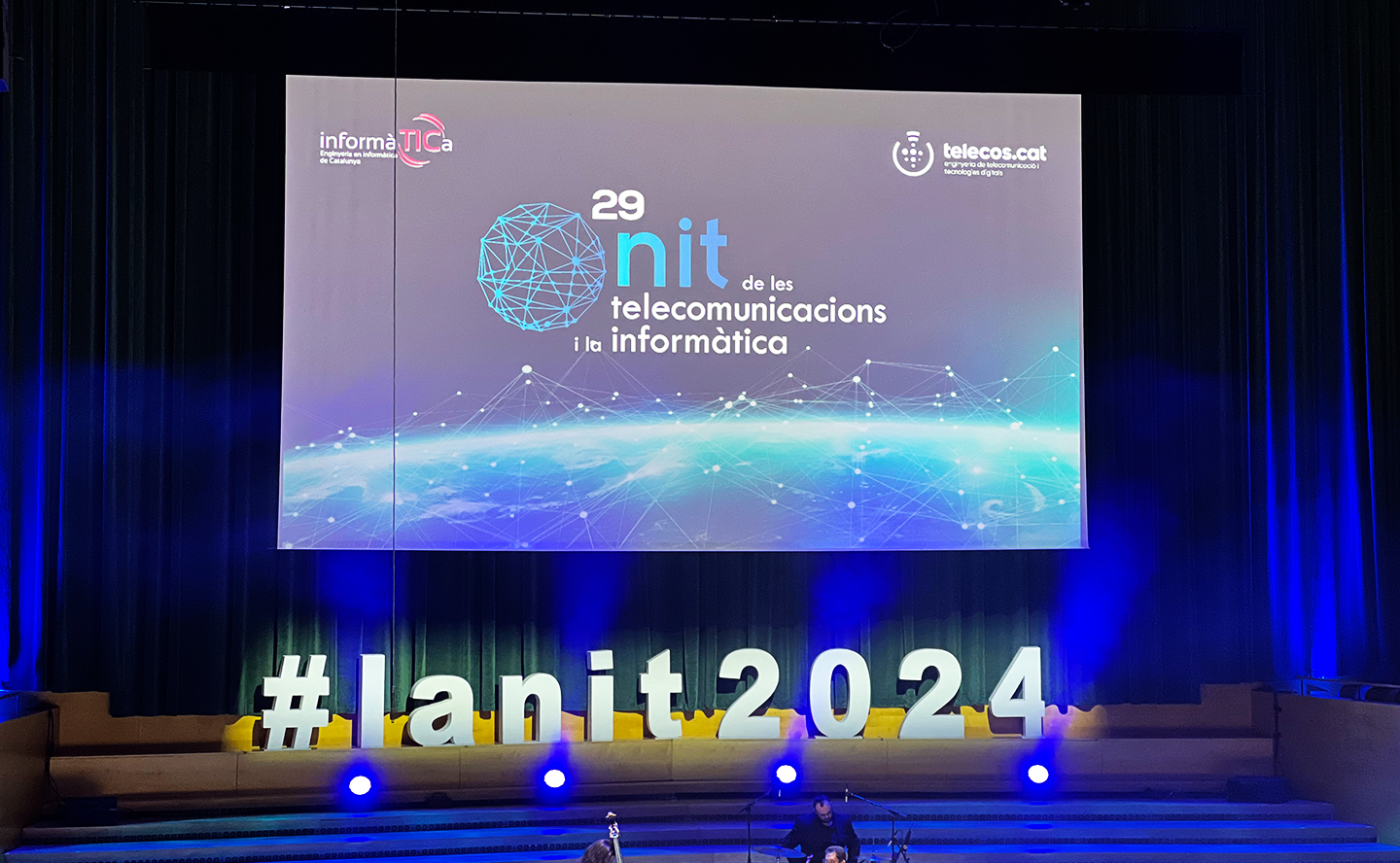 escenario con una pantalla del evento de la nit de les telecomunicacions i la informàtica 2024